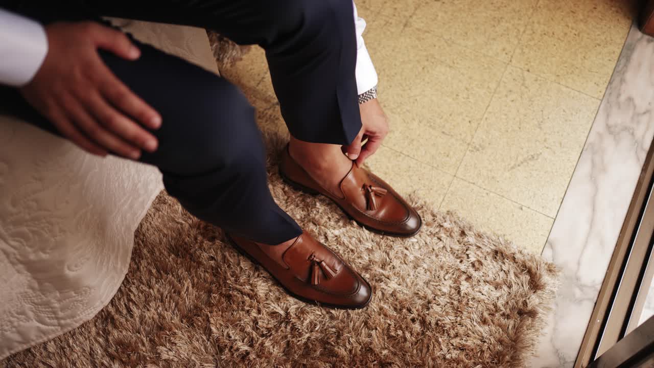 Penyesuaian anggun sepatu cokelat mengkilap di antara kain formal dalam cahaya interior yang hangat