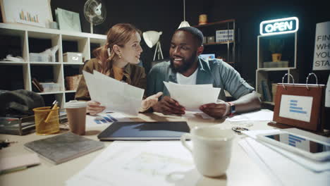 smiling afro man and woman finding great information in documents in office.