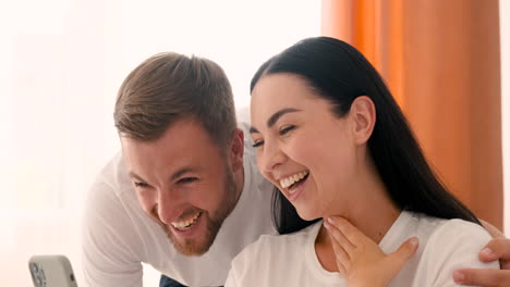 primer plano de una pareja sonriente que tiene una videollamada en un teléfono inteligente en casa 1