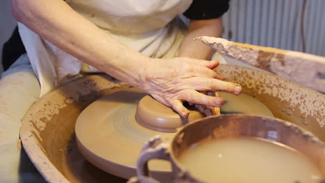 close up of male potter shaping clay on pottery wheel in ceramics studio