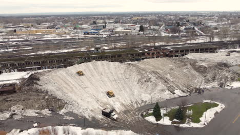 Aerial-top-view-over-snowplows-working-on-a-steep-hill-covered-with-snow