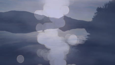 Animation of misty lake with bokeh light effects over calm water