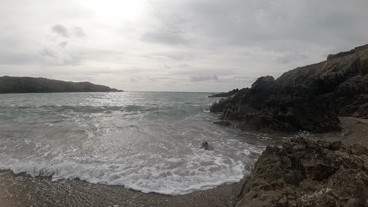 olas espumosas en cámara lenta chocando contra la escarpada costa galesa al amanecer