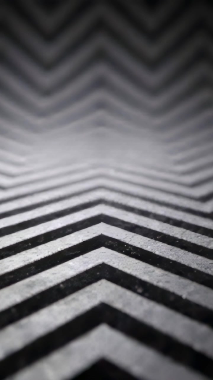 Vertical video: Racking camera focus after zoom on chevron pavement, keeping near stripes sharp