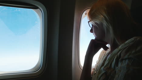 una mujer pensativa vuela en un avión mira por la ventana