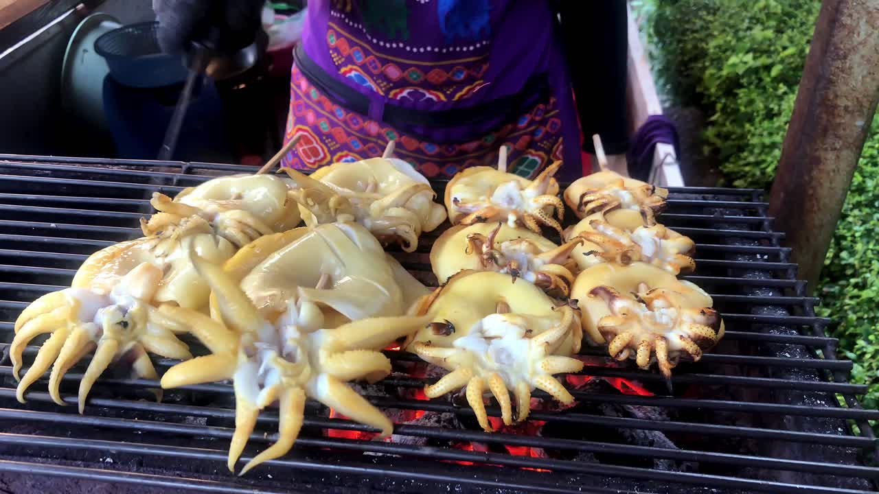 el vendedor de comida callejera es calamar fresco a la parrilla brochetas de carne asada con salsa