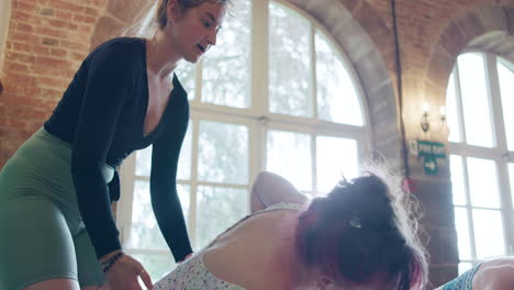 yoga instructor assisting a student with a pose