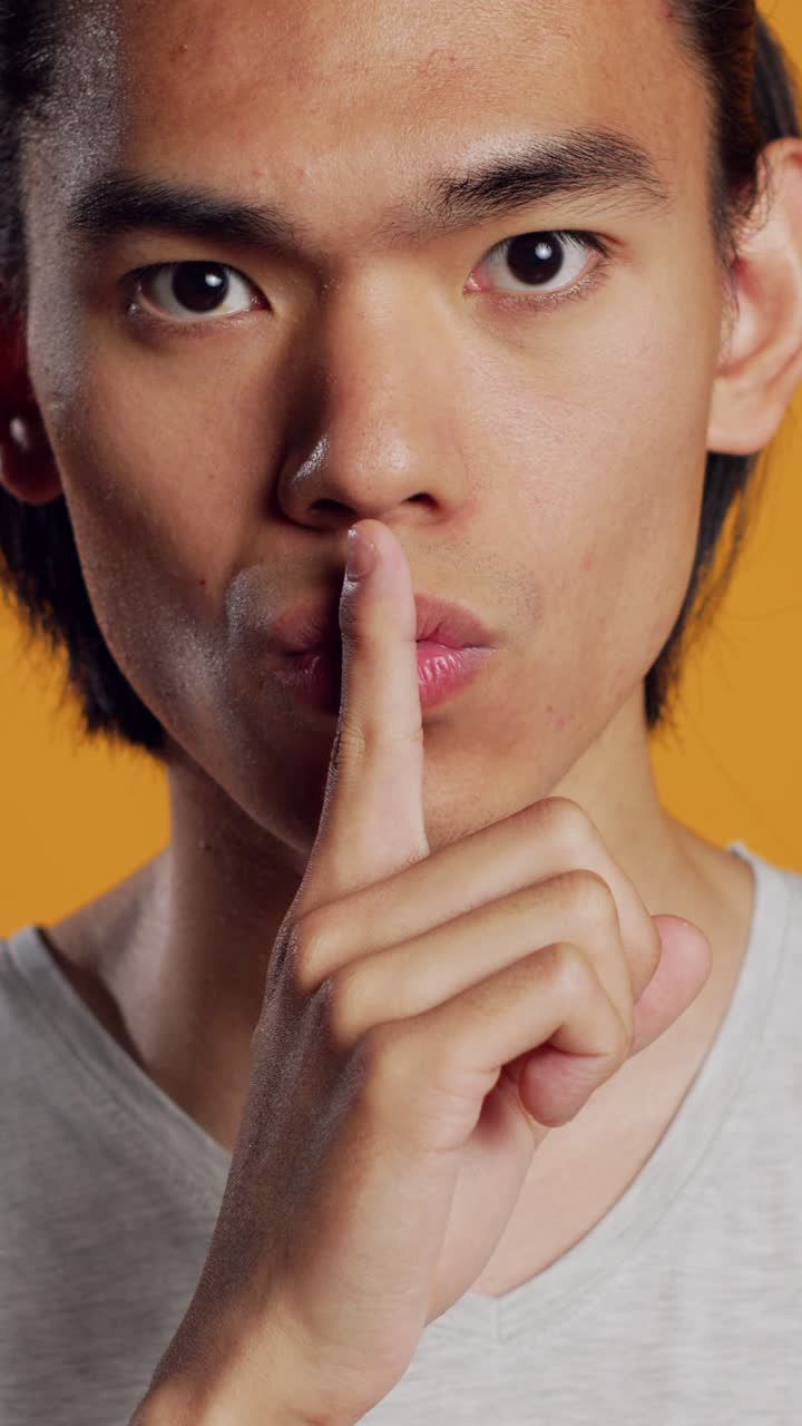 วิดีโอแนวตั้ง: ชายเอเชียส่วนตัวทำท่าทางให้เงียบต่อหน้ากล้อง