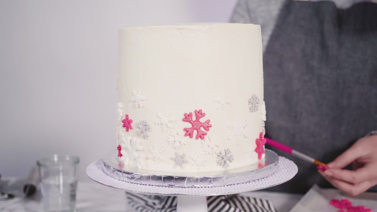 분홍색과 색의 폰던트 스노우플레이크로 둥근 페티 케이크를 장식합니다.
