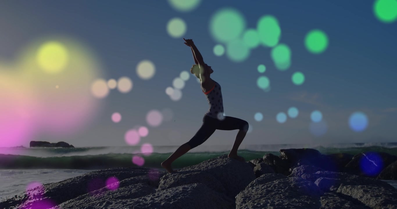 Donna che pratica yoga su una spiaggia rocciosa al tramonto