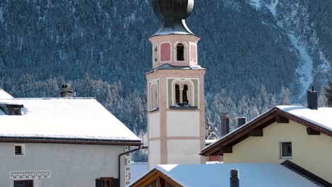 traditional church and houses in a swiss village with mountains in the background in switzerland