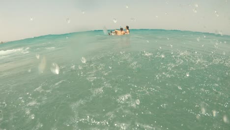 Sea wave. A man and a woman on an inflatable ring ride the sea on a wave.