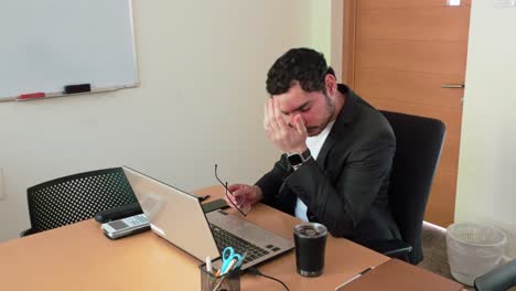a man is sitting at a desk with a laptop and a cup of coffee