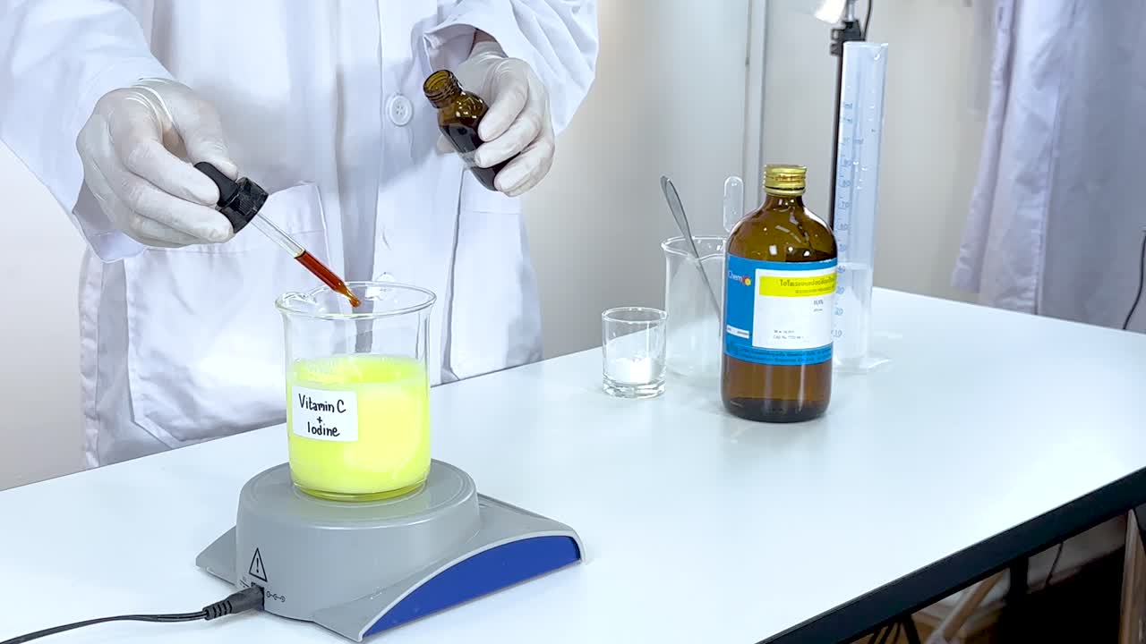 A scientist conducts an iodine clock reaction using vitamin C and starch in a lab setting with controlled lighting