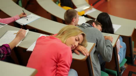 student asleep at desk in lecture hall