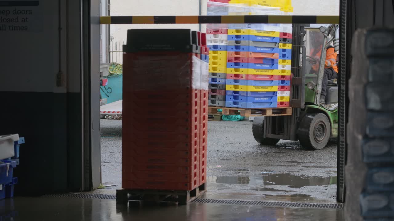 Toma estática de un conductor de carretilla elevadora moviendo palés de pescado a una fábrica de mariscos.