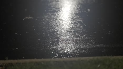 dark city street during rainfall with streetlight reflection