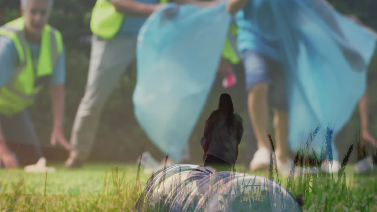 Animation of caucasian couple dancing on field over people collecting trash