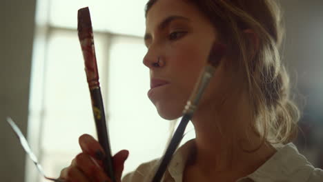 inspired painter looking in art studio. focused girl holding tools indoors.