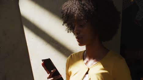 Happy-african-american-woman-standing-using-a-smartphone-and-smiling