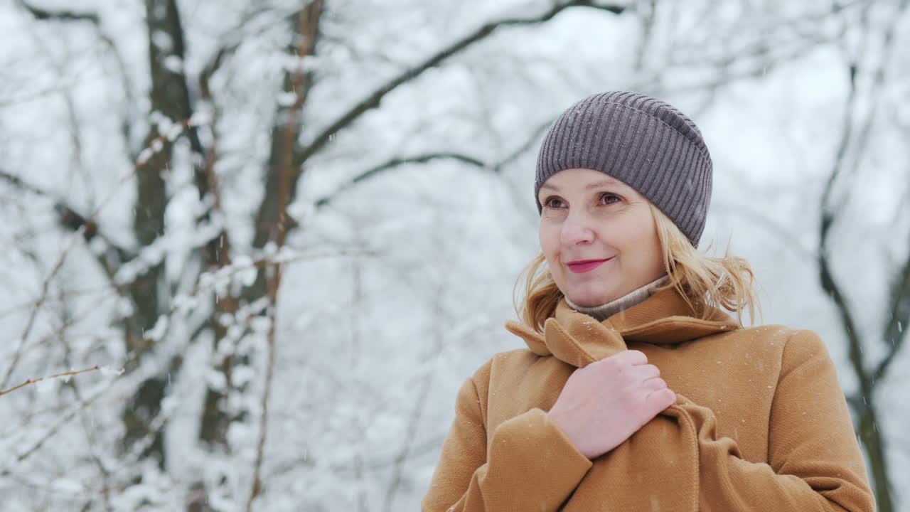 retrato de una mujer con un abrigo marrón parada en un hermoso parque cubierto de nieve