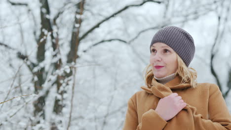 Porträt-Einer-Frau-In-Einem-Braunen-Mantel,-Die-In-Einem-Schneebedeckten-Schönen-Park-Steht