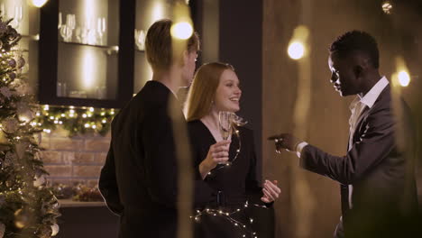 group friends wearing stylish clothes while talking and holding champagne glasses at new year's party 5