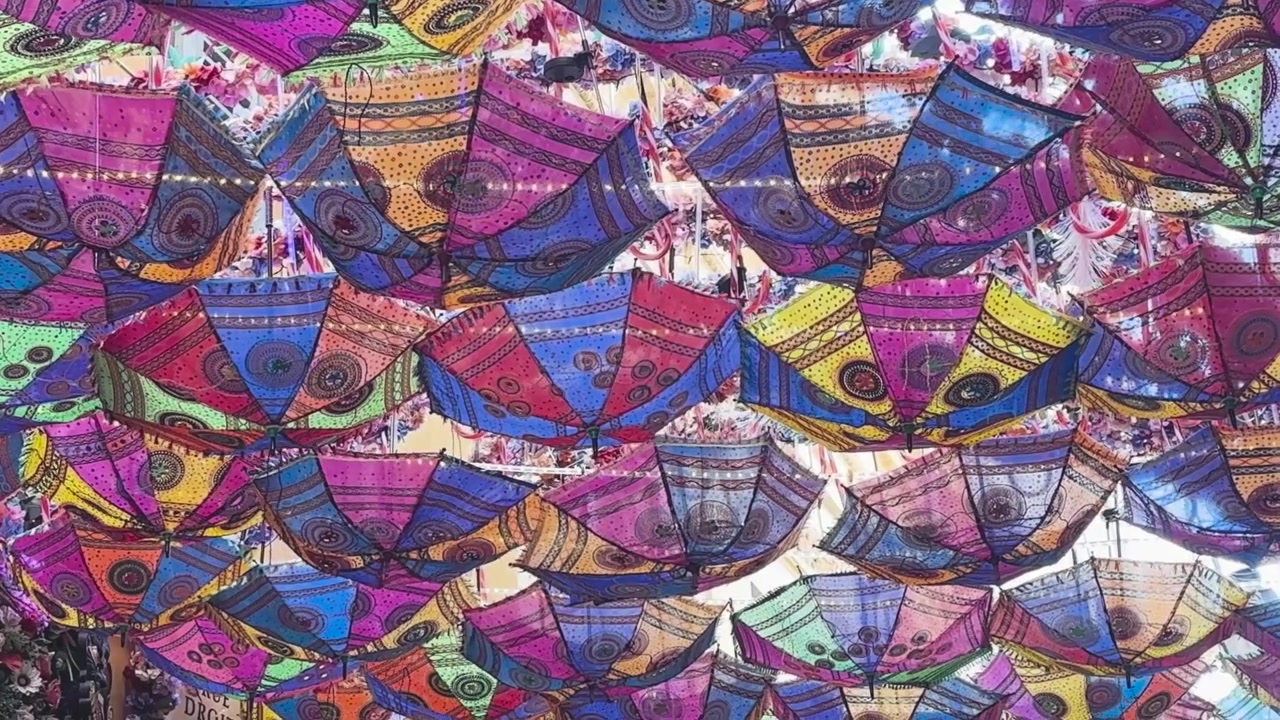 Vivaci file di ombrelli a fantasia creano una tettoia colorata in un mercato all'aperto a Nizza, Francia, sulla Costa Azzurra.
