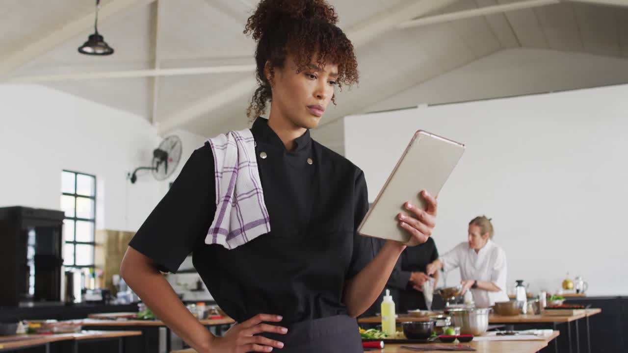 cocinera de raza mixta que usa una tableta digital