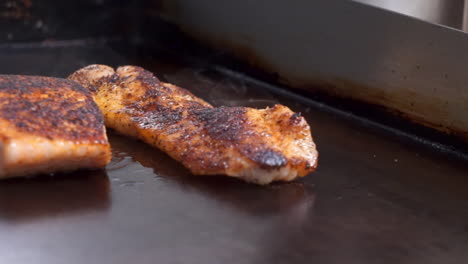 el salmón ennegrecido y la tilapia chisporrotean en una plancha superior plana, el pescado sazonado se sella en la plancha, hd