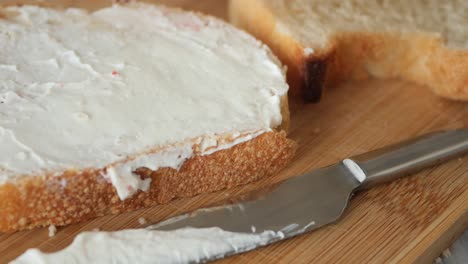 close up of a knife spreading butter on a piece of bread