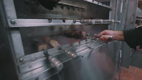 cook inspecting meat from restaurant oven