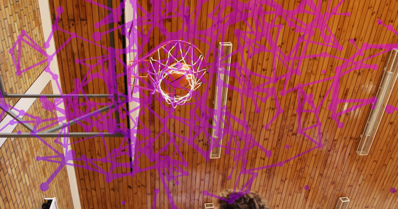 Three girls glancing at confetti in school gym before boy dribbling dunking basketball through hoop