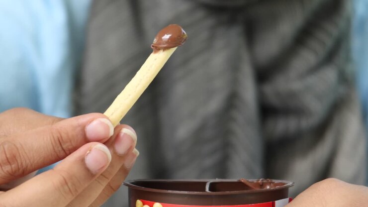 Mangiare grissino con crema spalmabile al cioccolato