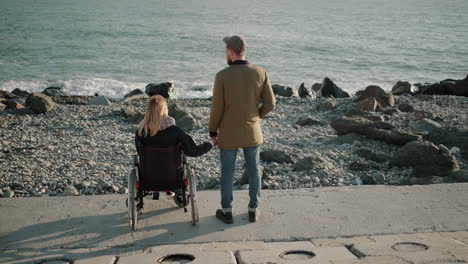 couple holding hands on the beach, a woman in a wheelchair