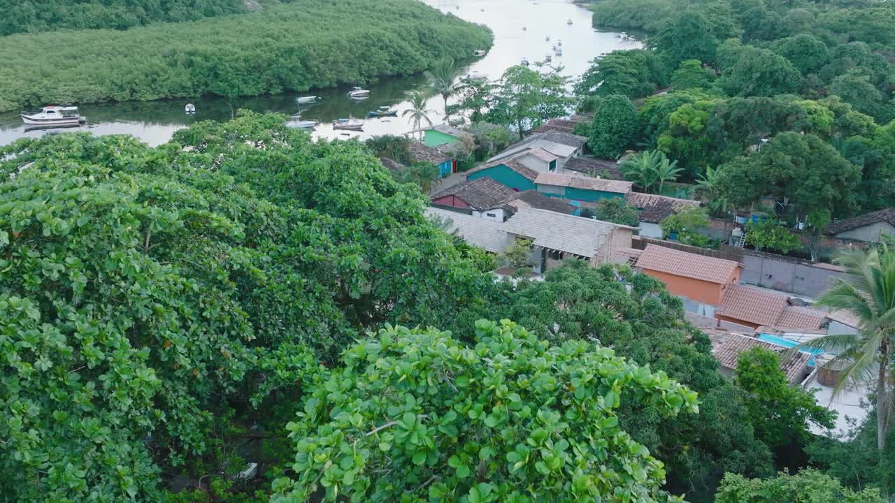 vista aérea de arriba hacia abajo de drones de la ciudad rural de caraiva bahia, brasil, volando sobre las copas de los árboles y el río con barcos