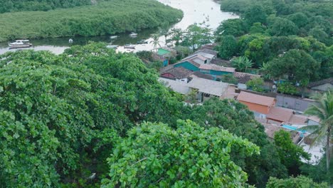 Luftaufnahme-Der-Ländlichen-Strandstadt-Caraiva-Bahia-Brasilien-Von-Oben-Nach-Unten,-Die-Mit-Booten-über-Baumwipfel-Und-Den-Fluss-Fliegt