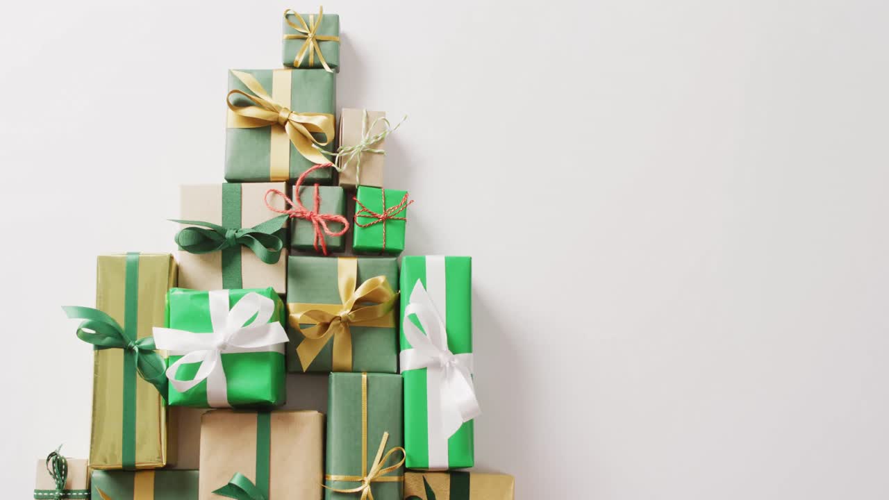 Video of christmas gifts forming christmas tree and copy space on white background