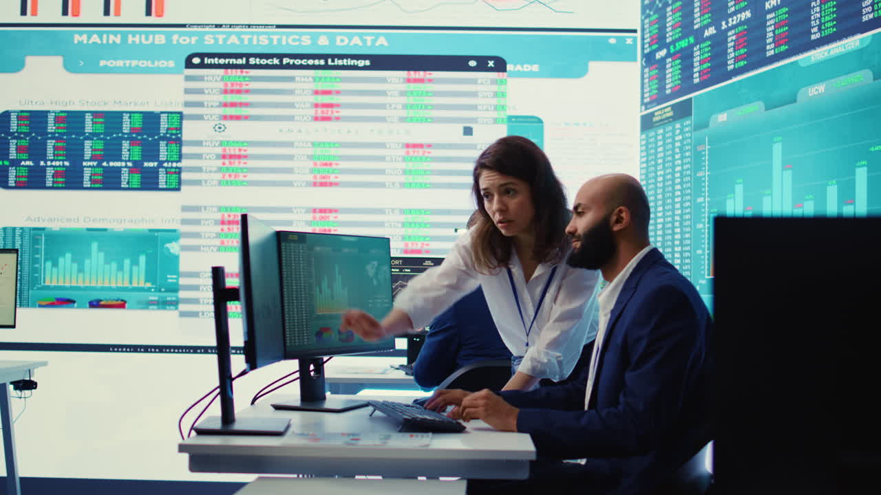 Teammates examining statistics and infographics on computer in control room