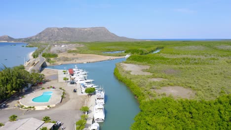 Aerial-shot-of-marina-harbor-with-docking-yachts-and-swimming-pool-at-Club-Náutico-De-Monte-Cristi-during-summer---Beautiful-river-and-Caribbean-Sea-surrounded-by-lush-mangroves