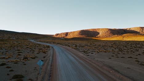 Drohnenaufnahmen-Bieten-Eine-Einzigartige-Perspektive-Von-Oben-Und-Zeigen-Die-Atemberaubende-Atacama-Wüste-Bei-Sonnenaufgang,-Während-Sich-Darunter-Eine-Autobahn-Durch-Die-Karge-Landschaft-Schlängelt