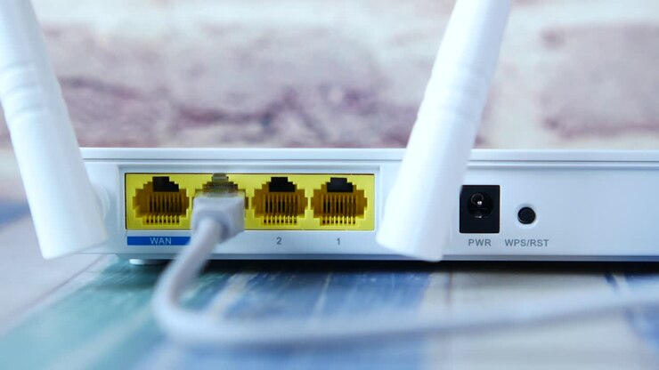 Close up of a white WiFi router back panel with ports and antennas.