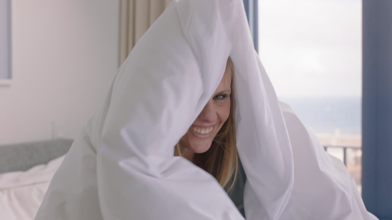 침대에서 놀고 있는 아름다운 여성이 침대  ⁇ 에서 즐겁게 놀고 있는 아침을 집에서 즐기고 있습니다.