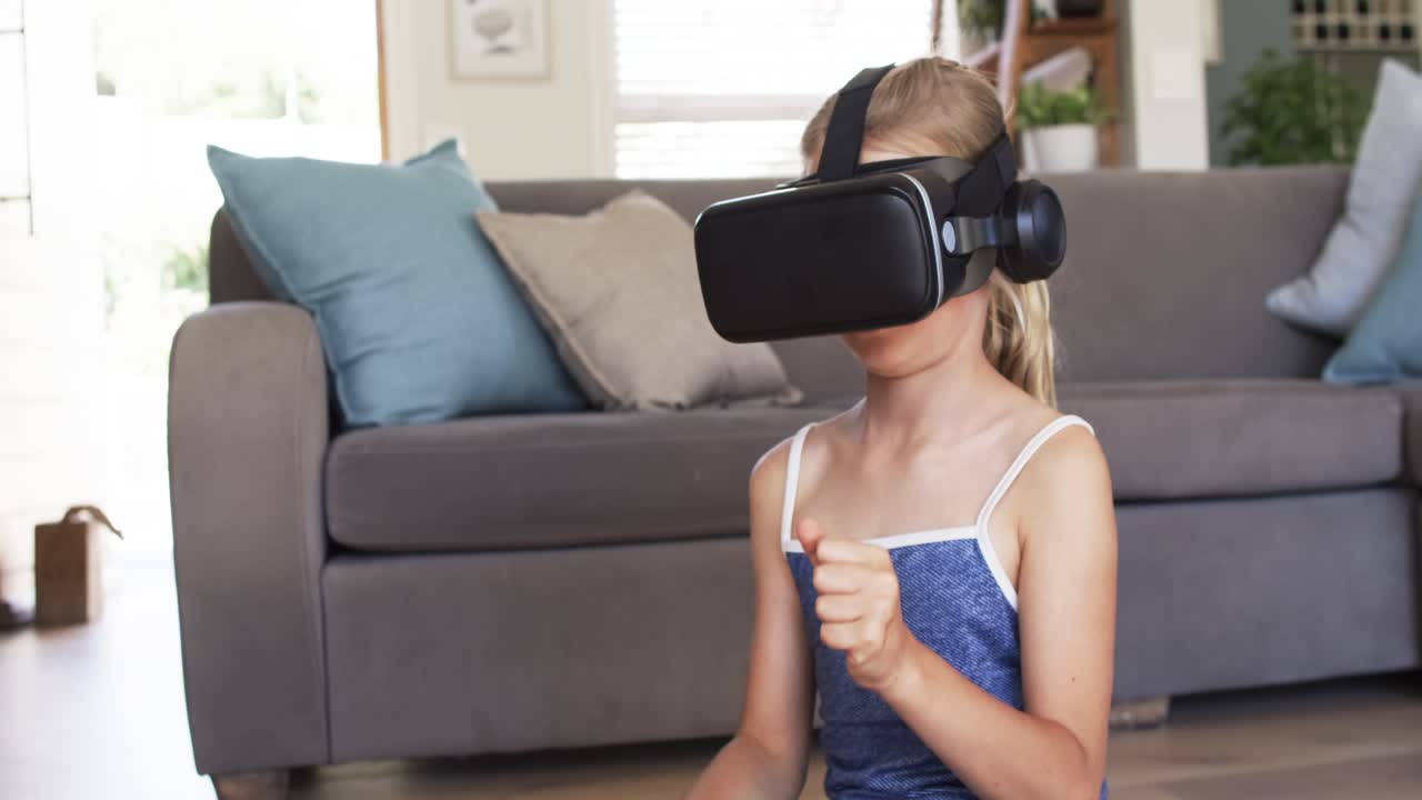 Female child wearing VR headset exploring virtual scene, reaching and pointing on floor by sofa