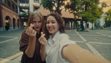 two friends taking a selfie in a city square