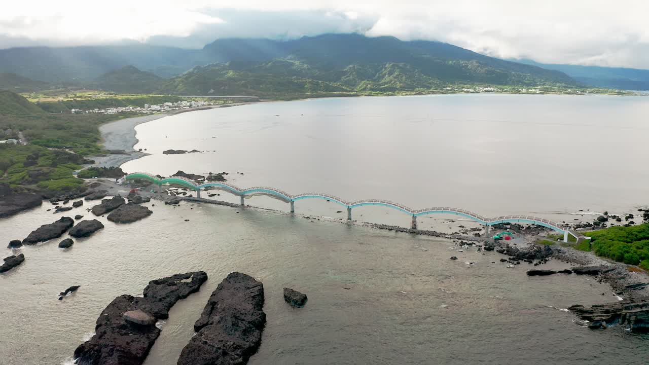 vista aérea del famoso puente de 8 arcos que se extiende desde el continente hasta un grupo de pequeñas islas en taiwán - montañas dramáticas con nubes en el fondo