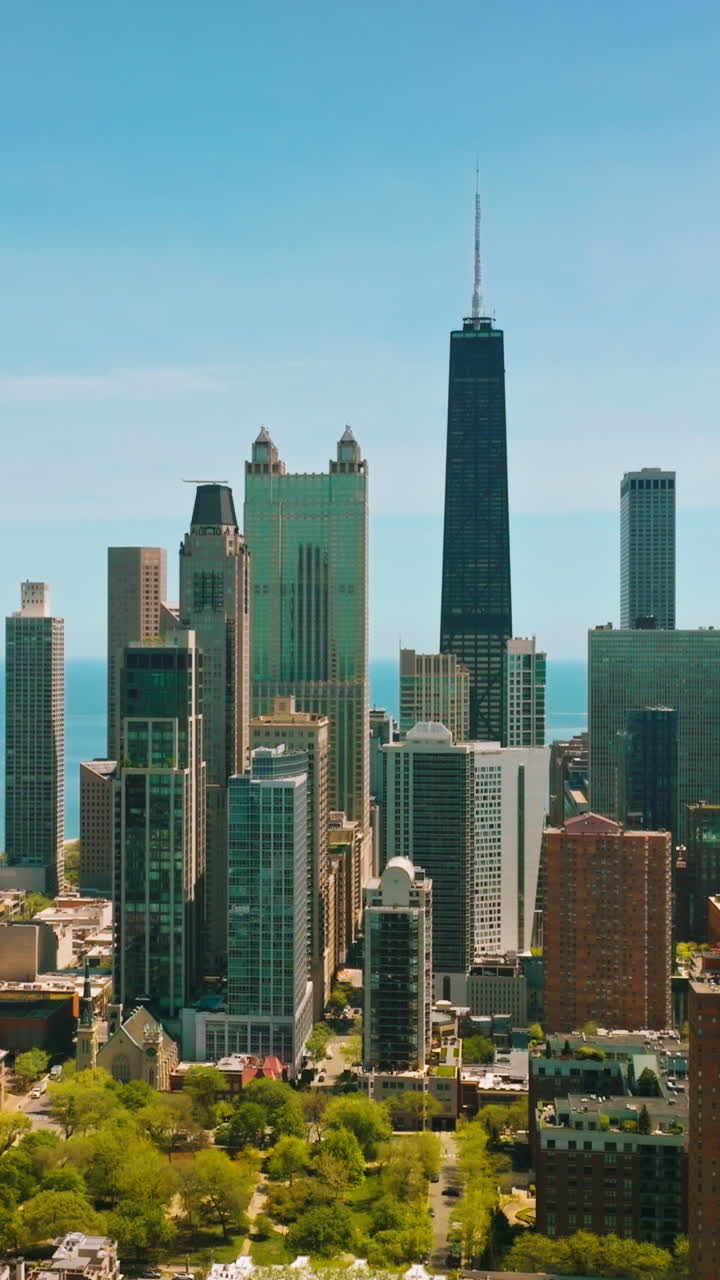 Green residential area with low multi-storied buildings. Modern beautiful skyscrapers against blue lake surface at backdrop. Vertical video