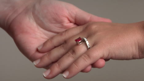 a man puts a gemstone ring on a woman's hand