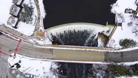 aerial upward pan of a waterfall near a bridge in winter