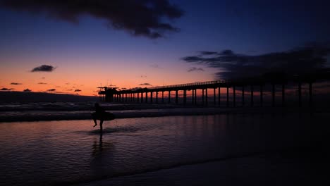 silueta de surfista caminando en la playa en la jolla, san diego al atardecer